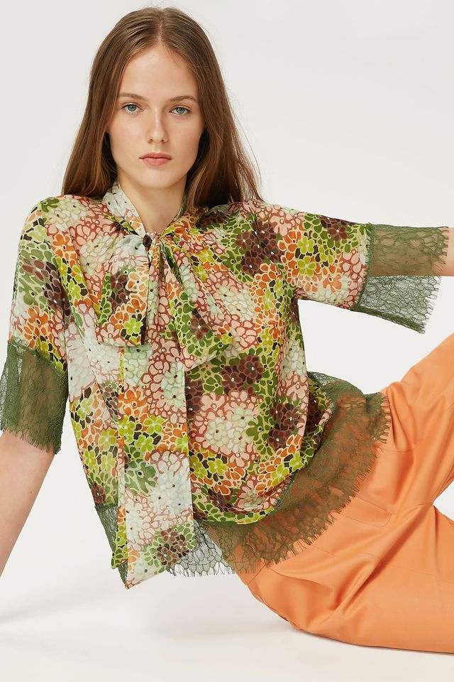 chica con blusa verde de flores y pantalón color naranja